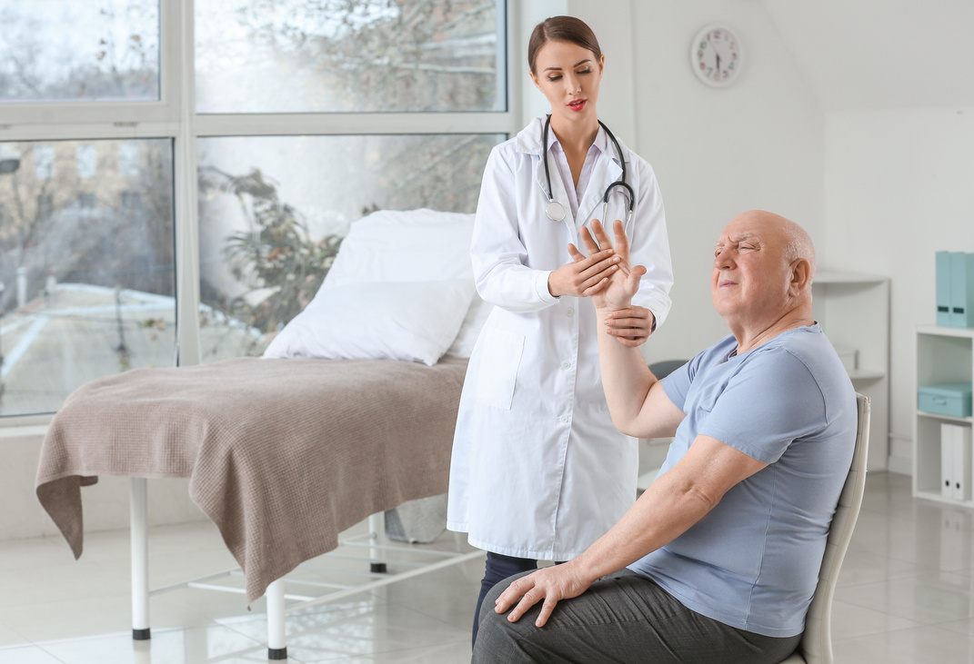 Female Doctor Working with Senior Man Suffering from Parkinson Syndrome in Clinic